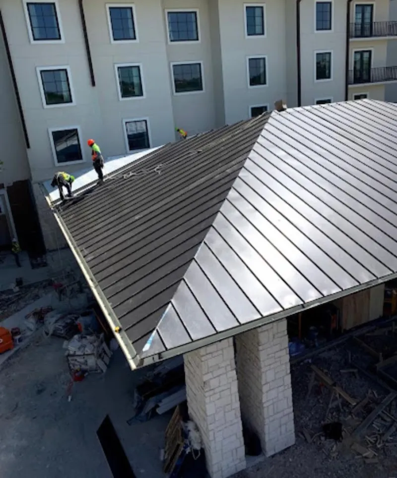 Crew installing standing seam metal roof panels on a commercial project in Livingston